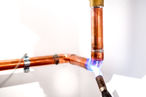 industrial plumber using blowtorch, propane gas torch for welding copper pipes