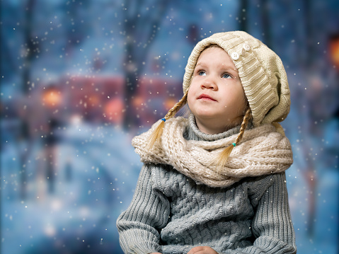 Wonderful little girl looks at the falling snowflakes, snow. Portrait