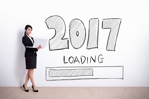 New Year is loading now - business woman using laptop computer with 2017 text and white wall background
