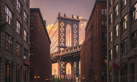 Manhattan bridge seen from a brick buildings in Brooklyn street in perspective, New York, USA. Shot in the evening