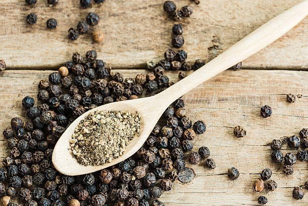istock grounded black pepper in wooden spoon 624265602