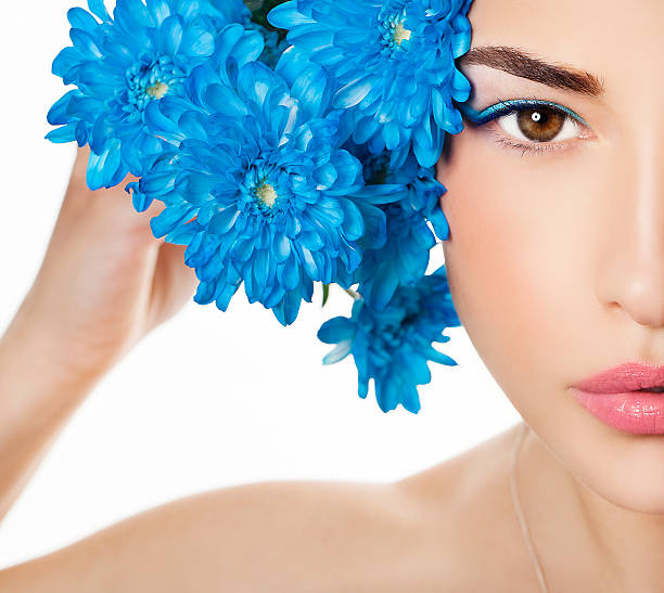 half face portrait of a beautiful woman with blue flowers close to head, macro portrait
