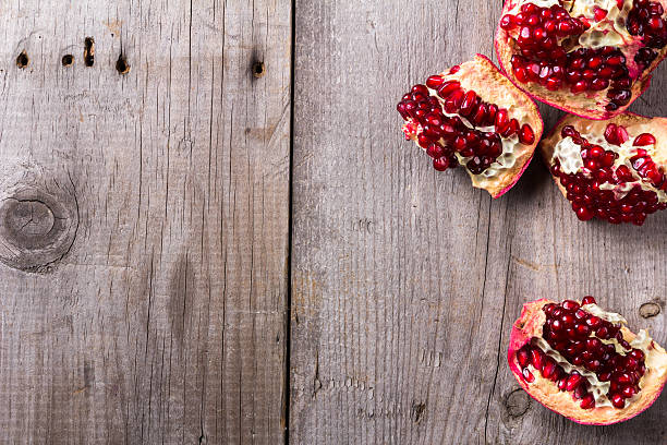 istock Broken red ripe juicy pomegranates on rustic wooden unpainted table 624266280