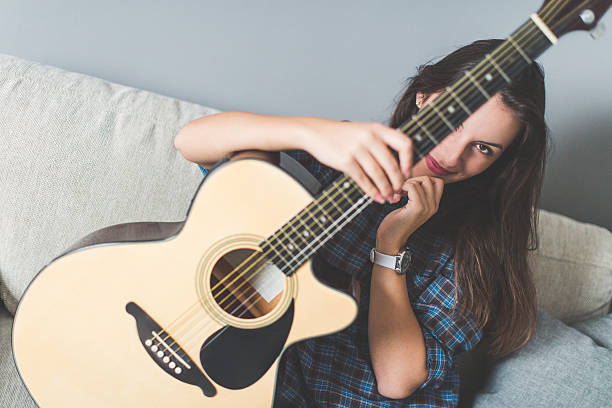 Young woman practicing guitar in living room