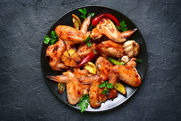Grilled chicken wings on a black plate.Top view.