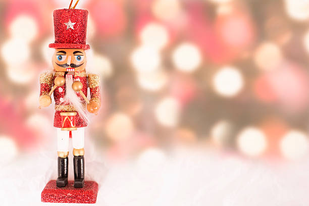 Red Christmas nutcracker ornament with colorful holiday lights. Close-up view of an elegant red Christmas nutcracker ornament on snow white background with colorful holiday lights.  Copyspace at side.  NOTE:  This image created for the Getty Creative Content Brief #663372617.   This ornament is not original artwork. nutcracker photos stock pictures, royalty-free photos & images