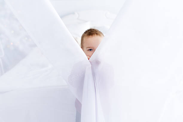 小さな男の子はカーテンのために隠れている - shy child little boys hiding ストックフォトと画像