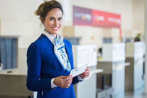 Stewardess looking at camera and holding a boarding pass