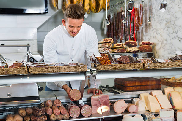 assistente in negozio di alimentari che saluta i clienti - bresaola foto e immagini stock