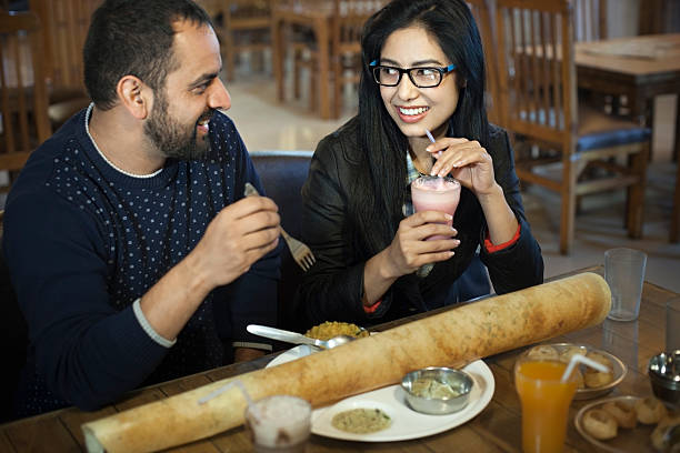 レストランで南インド料理を食べる多民族の若いカップル。 - south india ストックフォトと画像