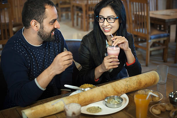 multi ethnic young couple eating south indian food at restaurant. - dosa imagens e fotografias de stock