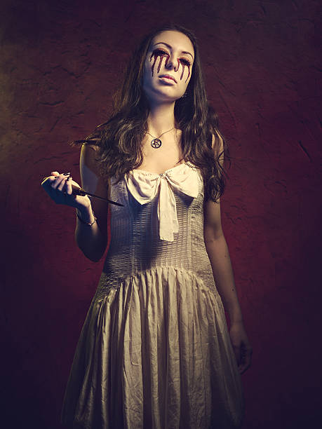 istock Vampire girl with a knife. Blood leaks from her eyes 624407702