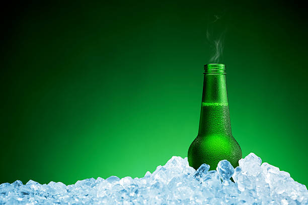 istock Bottle of cold beer in ice on green background 624438006