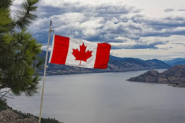 Canadian Flag flies over Okanagan Lake near Peachland British Columbia Canada on a windy day