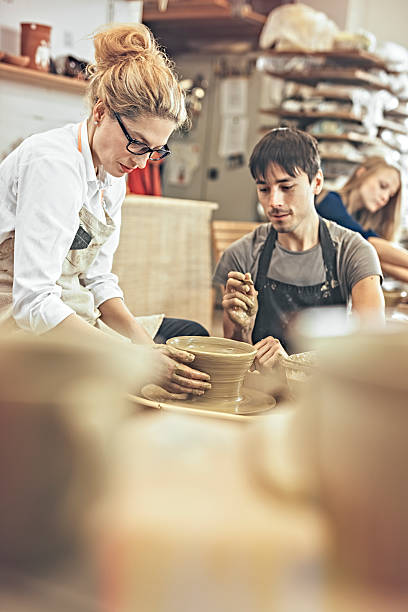 istock Man and woman in workshop working on pottery wheel 624443344