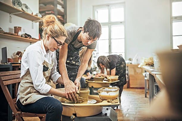 istock Man and woman in workshop working on pottery wheel 624443530