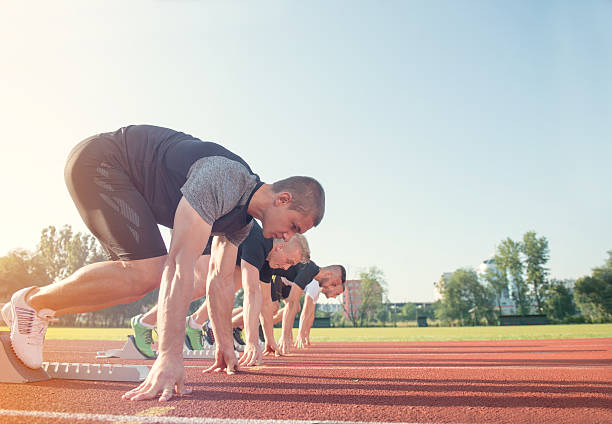 vista laterale ravvicinata delle persone pronte a correre in pista - rivalry starting block track and field athlete track and field foto e immagini stock