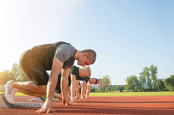 vista laterale ravvicinata delle persone pronte a correre in pista - rivalry starting block track and field athlete track and field foto e immagini stock