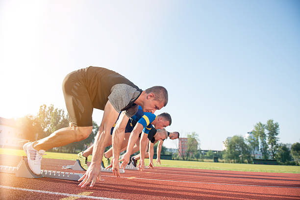 vista laterale ravvicinata delle persone pronte a correre in pista - rivalry starting block track and field athlete track and field foto e immagini stock