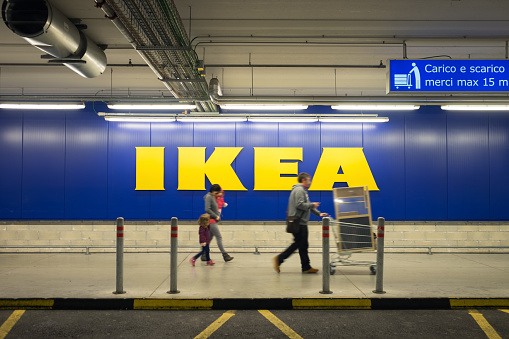 Chieti, Italy - November 19, 2016: A family walking in the car parking after shopping at Ikea store; the big sign of the store is in the background. Ikea is one of the largest (if not the largest)  ready-to-assemble furniture retailer.