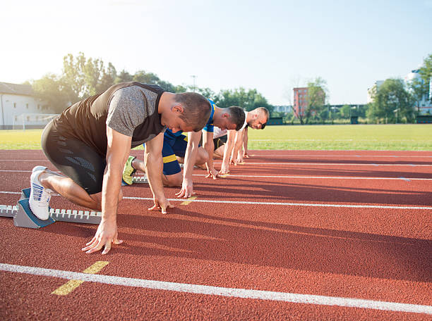 vista laterale ravvicinata delle persone pronte a correre in pista - rivalry starting block track and field athlete track and field foto e immagini stock