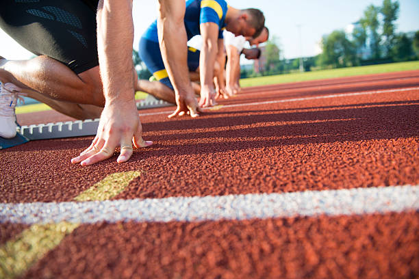 vista laterale ravvicinata delle persone pronte a correre in pista - rivalry starting block track and field athlete track and field foto e immagini stock