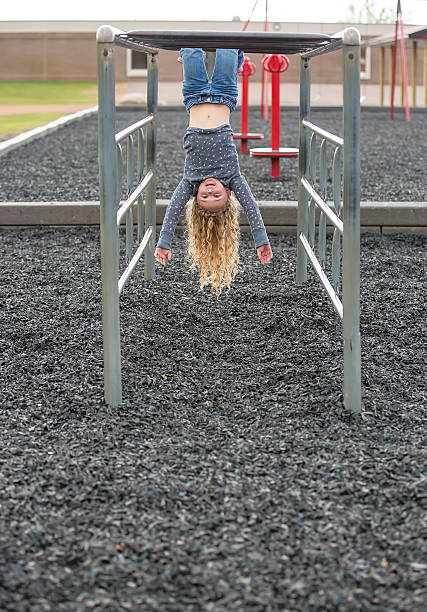 istock Girl Hanging Upside Down on Monkey Bars 624474010
