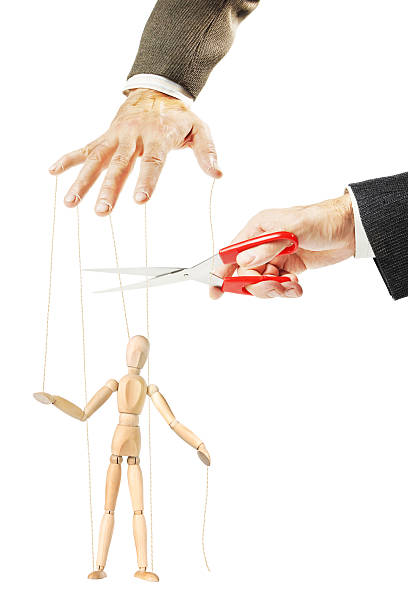 istock Man cuts threads of a wooden puppet. Concept of release 624490682