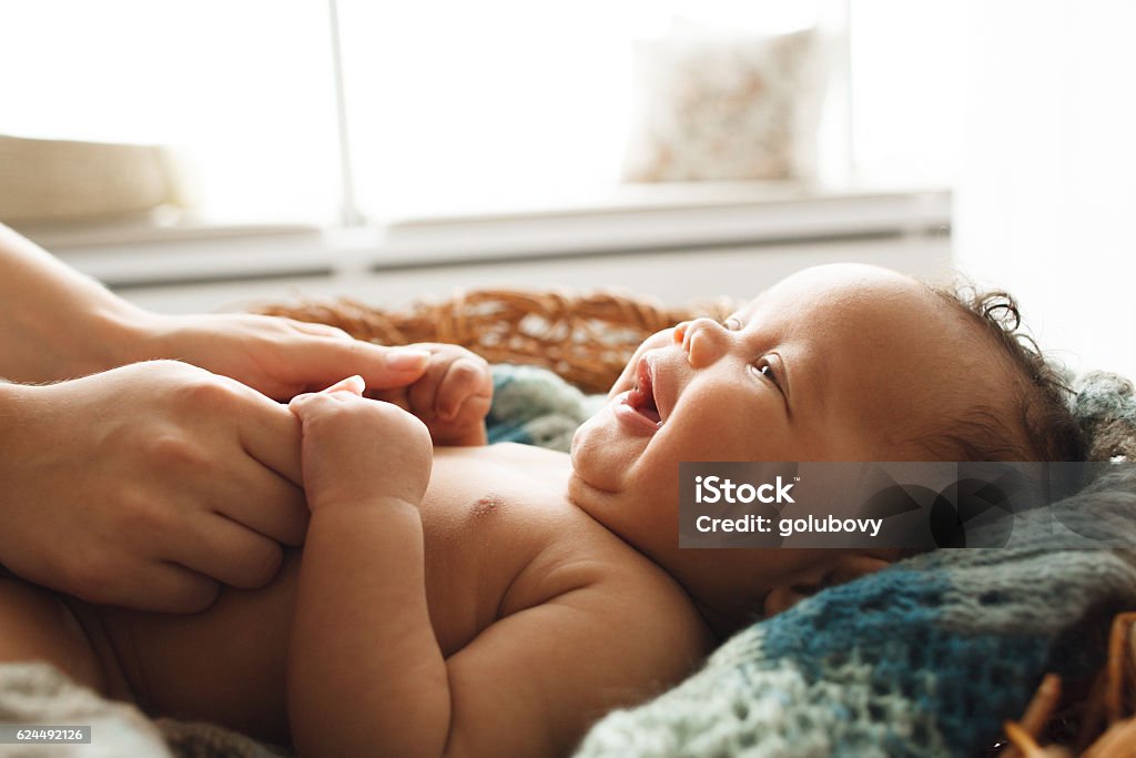 Baby smiling at mother, close-up Baby smiling at mother, close-up. Adorable newborn child looking up at mother and holding her hands. Love, innocence, cuteness concept Baby - Human Age Stock Photo