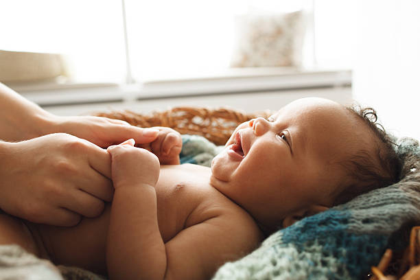 Baby smiling at mother, close-up Baby smiling at mother, close-up. Adorable newborn child looking up at mother and holding her hands. Love, innocence, cuteness concept cute black babys stock pictures, royalty-free photos & images