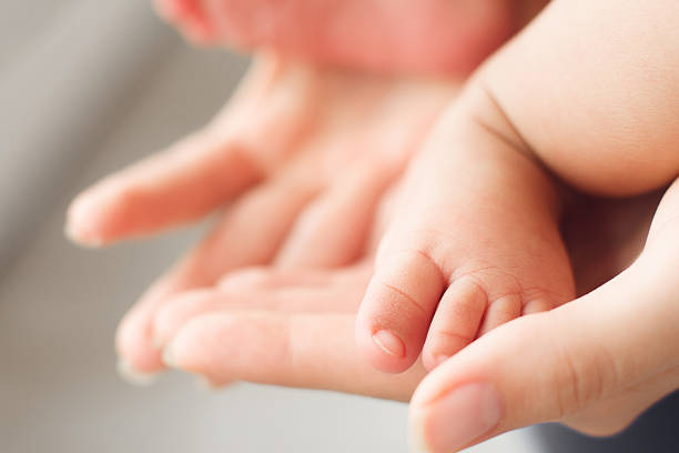 pequeño pie de bebé recién nacido en manos femeninas, primer plano - barefoot behavior toned image close up fotografías e imágenes de stock