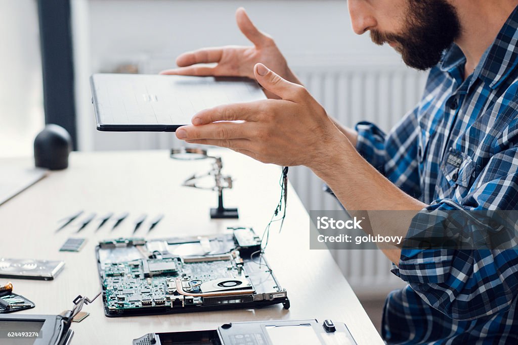 Laptop disassembling at electronic repair shop Laptop disassembling at electronic repair shop. Side view on bearded engineer separating computer from case. Electronic renovation, business, occupation concept Repairing Stock Photo