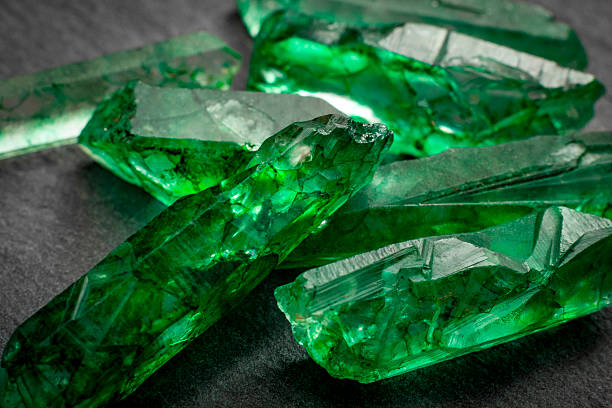 Macro image of raw jewels Closeup of a bunch of many green rough uncut emerald crystals emerald gemstone stock pictures, royalty-free photos & images