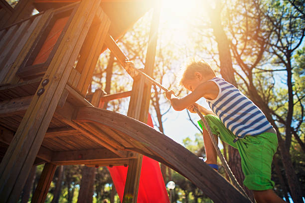 kleiner junge klettert auf dem spielplatz - kinderspielplatz stock-fotos und bilder