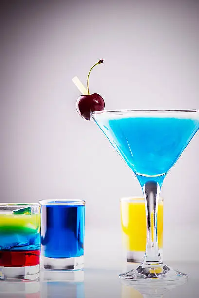 Photo of Glass of long drink with mixed colored alcoholic shots