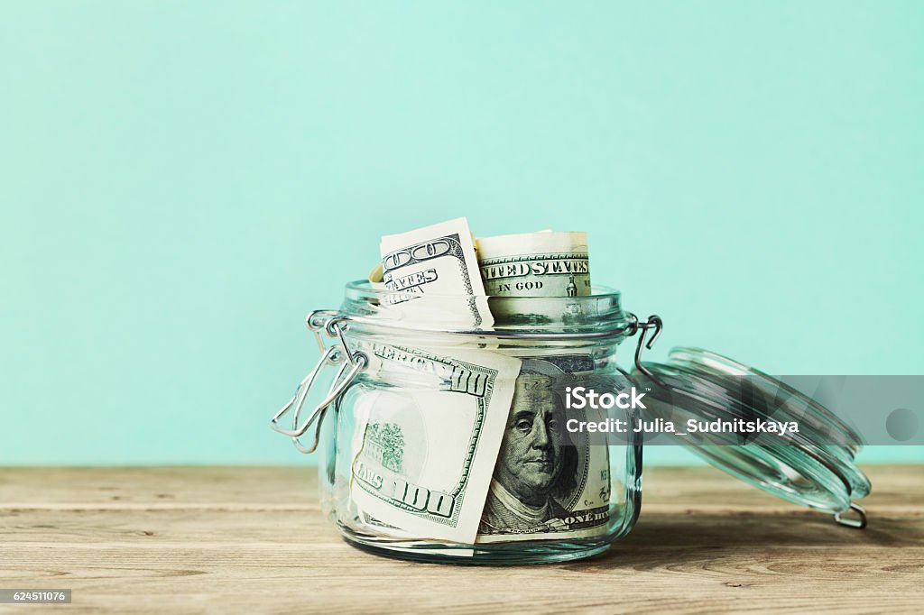 Dollar bills in glass jar. Saving money, economy, finance concept. Dollar bills in glass jar on wooden table. Saving money concept. Currency Stock Photo