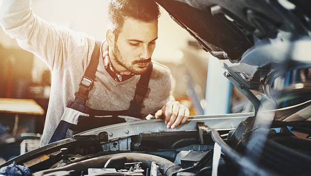 mécanicien automobile inspectant le moteur pendant la procédure d’entretien. - garage sale flash photos et images de collection