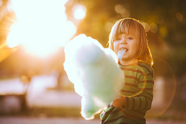 Baby Boy Eating Candyfloss Young boy with some blue colored cotton candy at an amusement park child cotton candy stock pictures, royalty-free photos & images