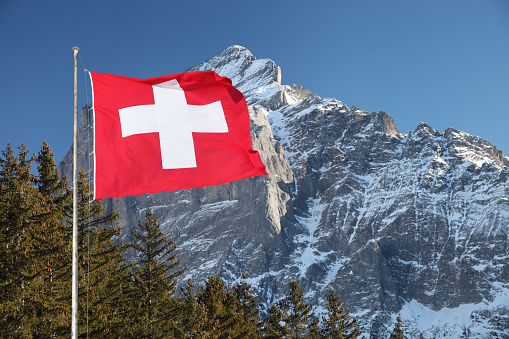 Swiss flag waving in Alps mountains