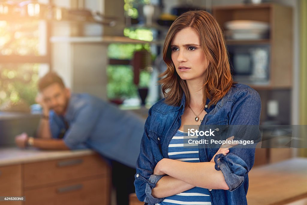 When poor communication causes conflict Shot of a young woman looking upset after a fight with her husband who is standing in the background Women Stock Photo