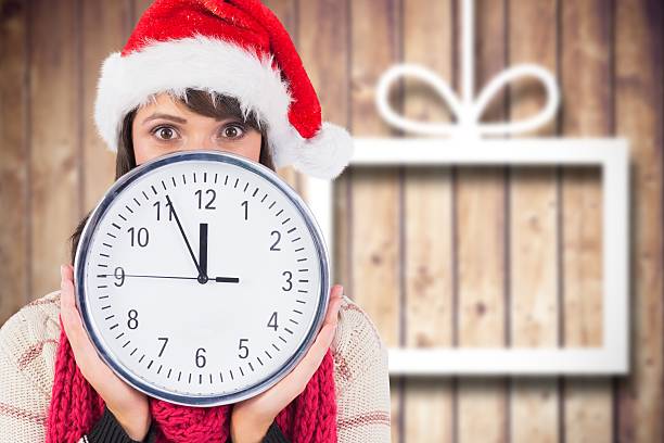istock Woman in santa hat covering her face behind clock 624531450