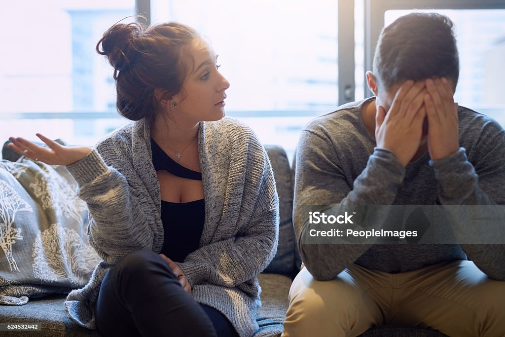 Don't you have ANYTHING to say?! Shot of a young woman scolding her boyfriend in their home Couple - Relationship Stock Photo