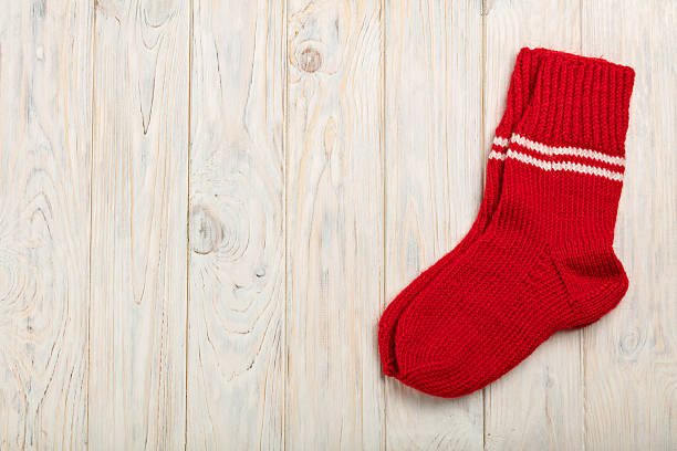 istock Knitted wool socks in red on a light wooden background. 624541186