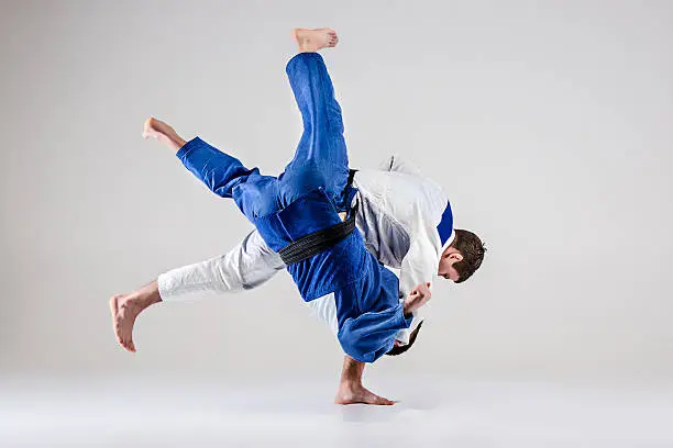 The two judokas fighters fighting men on gray studio background