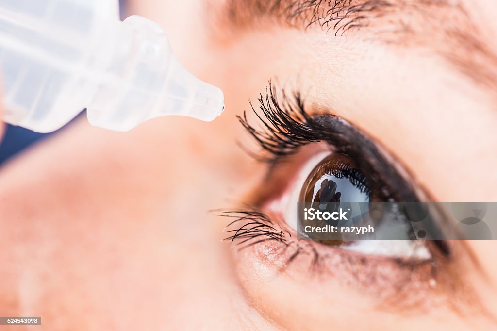 Eyedropper near eye Bucharest, Romania - June 18,2016 : Closeup of eyedropper preparing to release fluid drops in the brown eye Eye Stock Photo