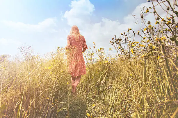 Photo of dreamy woman walking in nature towards the sun