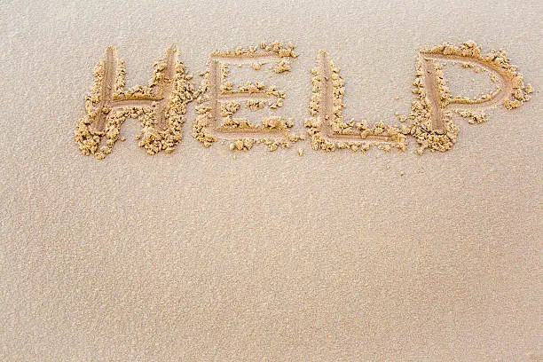 Help word drawn on wet sand by the waves on the shore. Background.