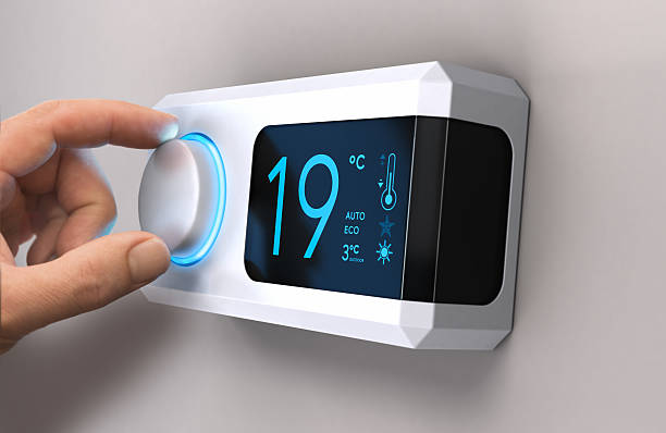 Save Energy, Reducing Electricity Use Hand turning a home thermostat knob to set temperature on energy saving mode. celcius units. Composite image between a photography and a 3D background. heat temperature stock pictures, royalty-free photos & images