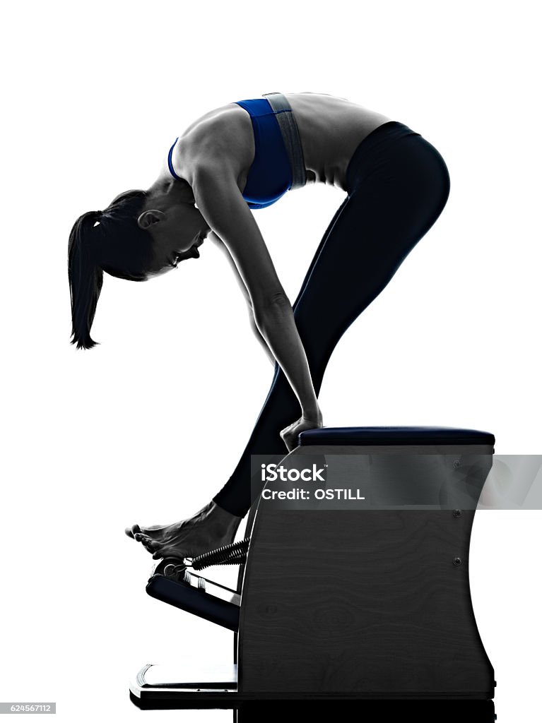 woman pilates chair exercises fitness isolated one caucasian woman exercising pilates chair exercises fitness in silhouette isolated on white backgound Pilates Stock Photo