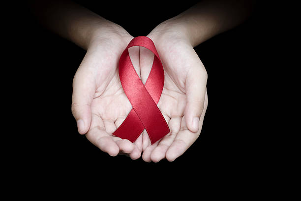 hand holding red ribbon on black background - world aids day stok fotoğraflar ve resimler